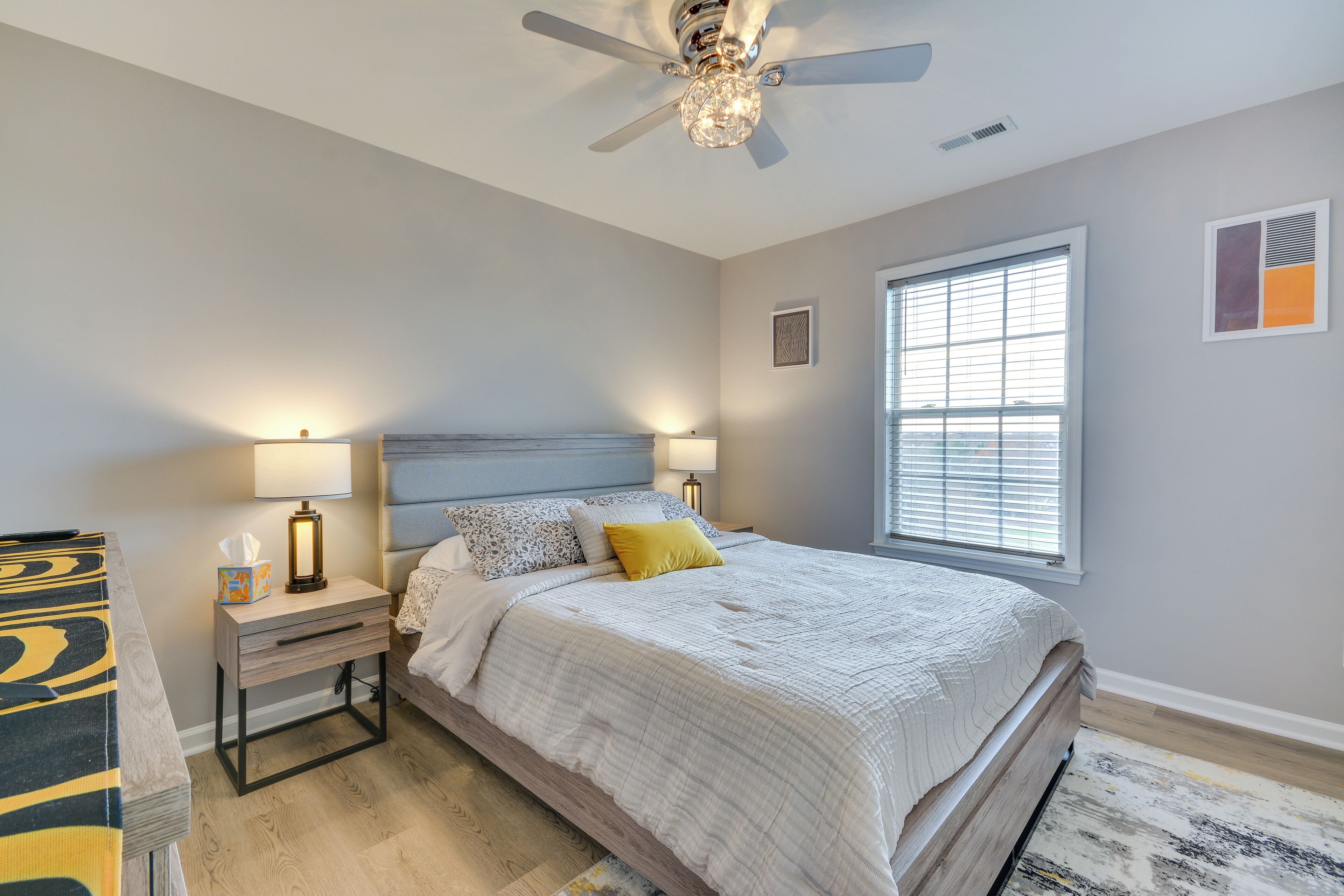 A bedroom with a bed, nightstands, a ceiling fan, and a window.