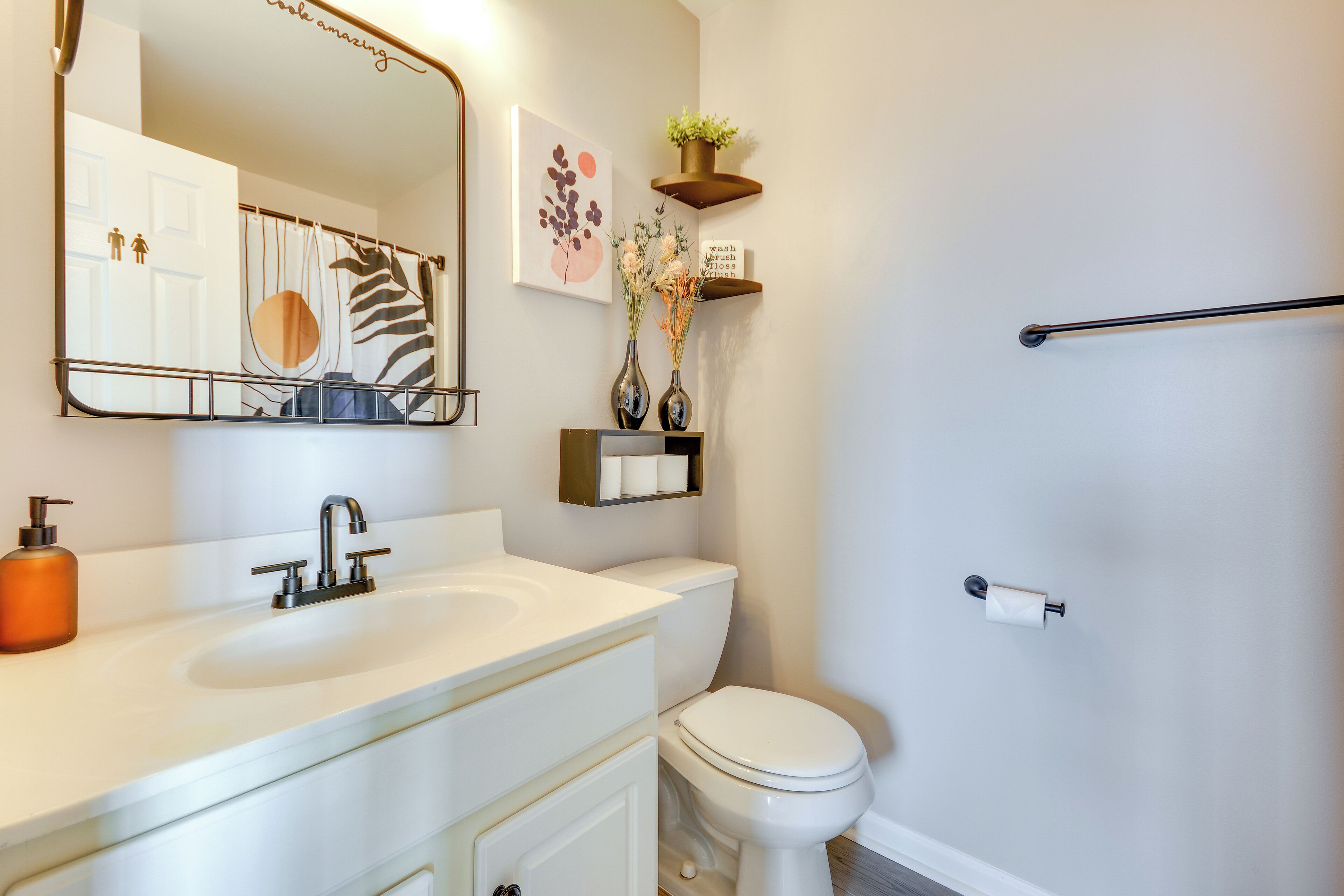 Une salle de bain avec un lavabo blanc, des toilettes, un miroir et un porte-serviettes.