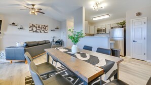 Un salon moderne comprenant un canapé, une table à manger et des chaises. Il y a également un coin cuisine avec un réfrigérateur et un four à micro-ondes.