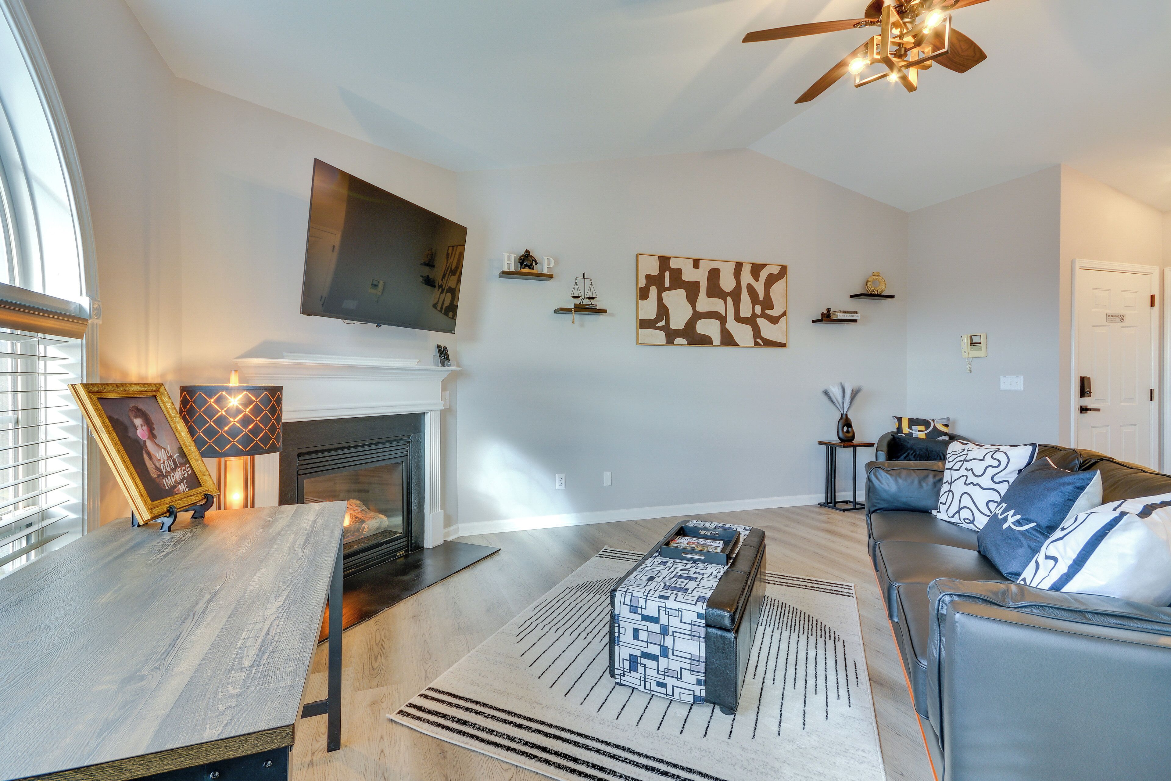 A modern living room with a fireplace, a sofa, a coffee table, and a TV mounted on the wall.
