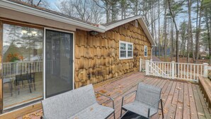 Eine Holzhütte mit einer Terrasse, großen Schiebegläsern und zwei grauen Stühlen.