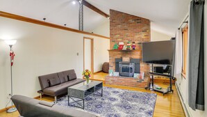 Ein Wohnzimmer mit Kamin, Sofa, Couchtisch und Fernseher.