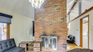 Ein modernes Wohnzimmer mit Kamin aus Backstein, einer Couch, einem Couchtisch und einer Treppe, die zu einer oberen Ebene führt.