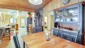 Una cocina acogedora con paredes de madera, una chimenea de ladrillo y una zona de comedor con una mesa y sillas de madera.