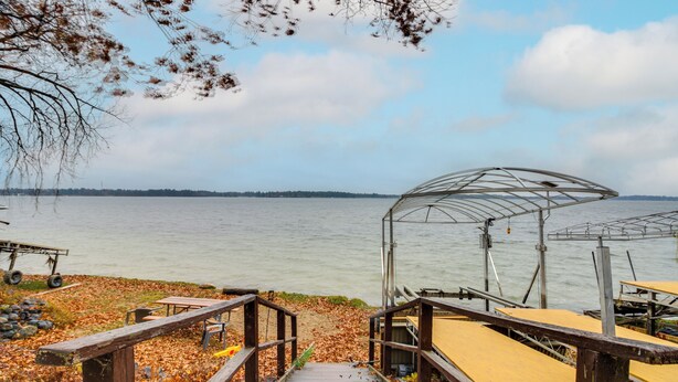 Un muelle de madera que lleva a un área de descanso cubierta junto a un lago.
