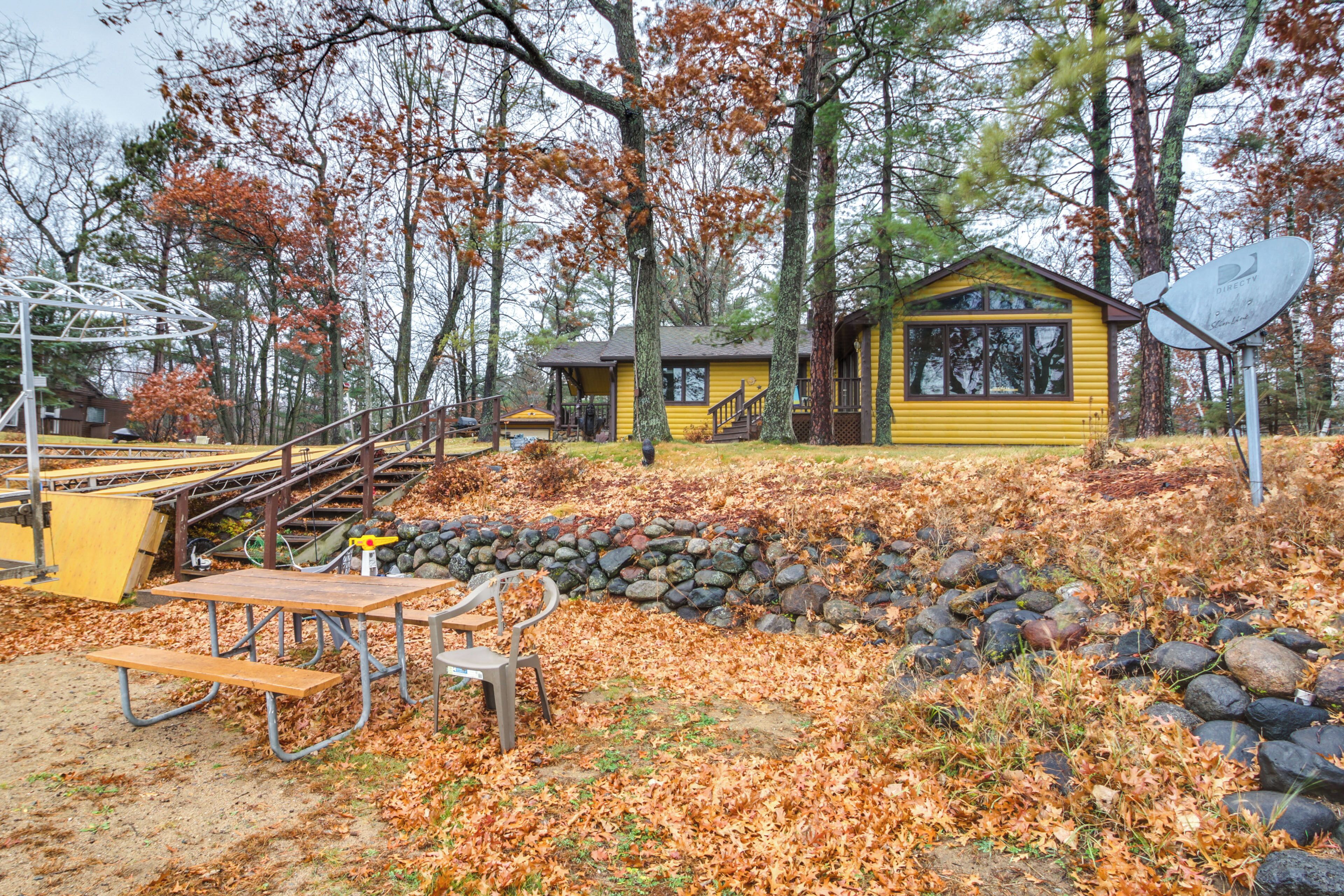 Un chalet rustique avec un mur en pierre et une table de pique-nique, situé dans une zone boisée.