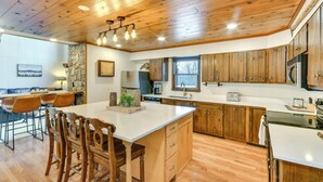 A spacious kitchen with wooden cabinets, a large island, and a dining area with chairs. - 6 Mi to Skiing! Hot Tub Hideaway in Seven Devils (Banner Elk)
