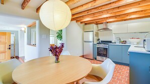 A modern kitchen with wooden beams, a round dining table, and white chairs. - 3 Mi to Downtown - Condo w/ Hot Tub in Santa Fe! (Santa Fe)