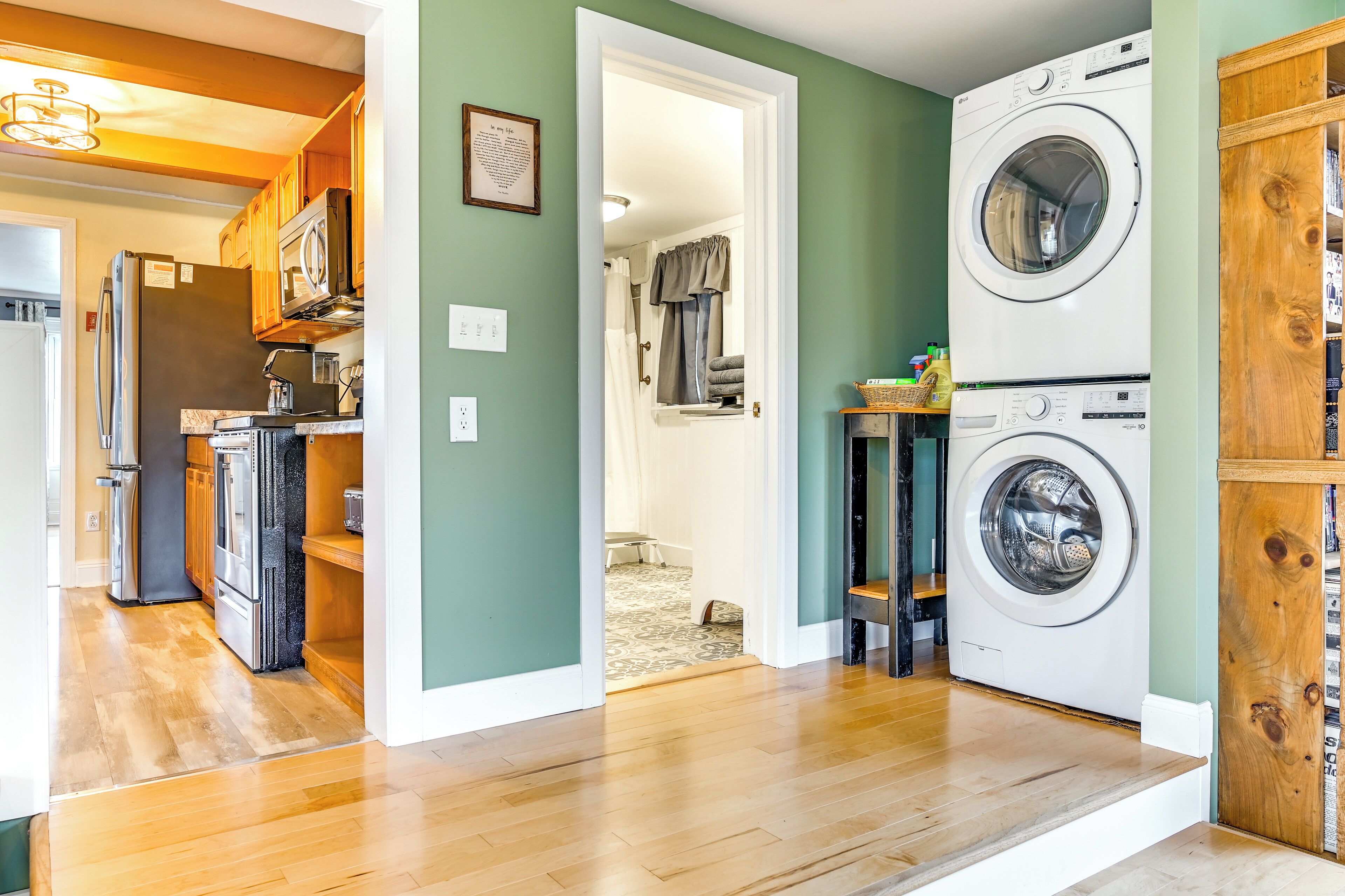 A compact laundry room with a washing machine and dryer, wooden cabinets, and a microwave.