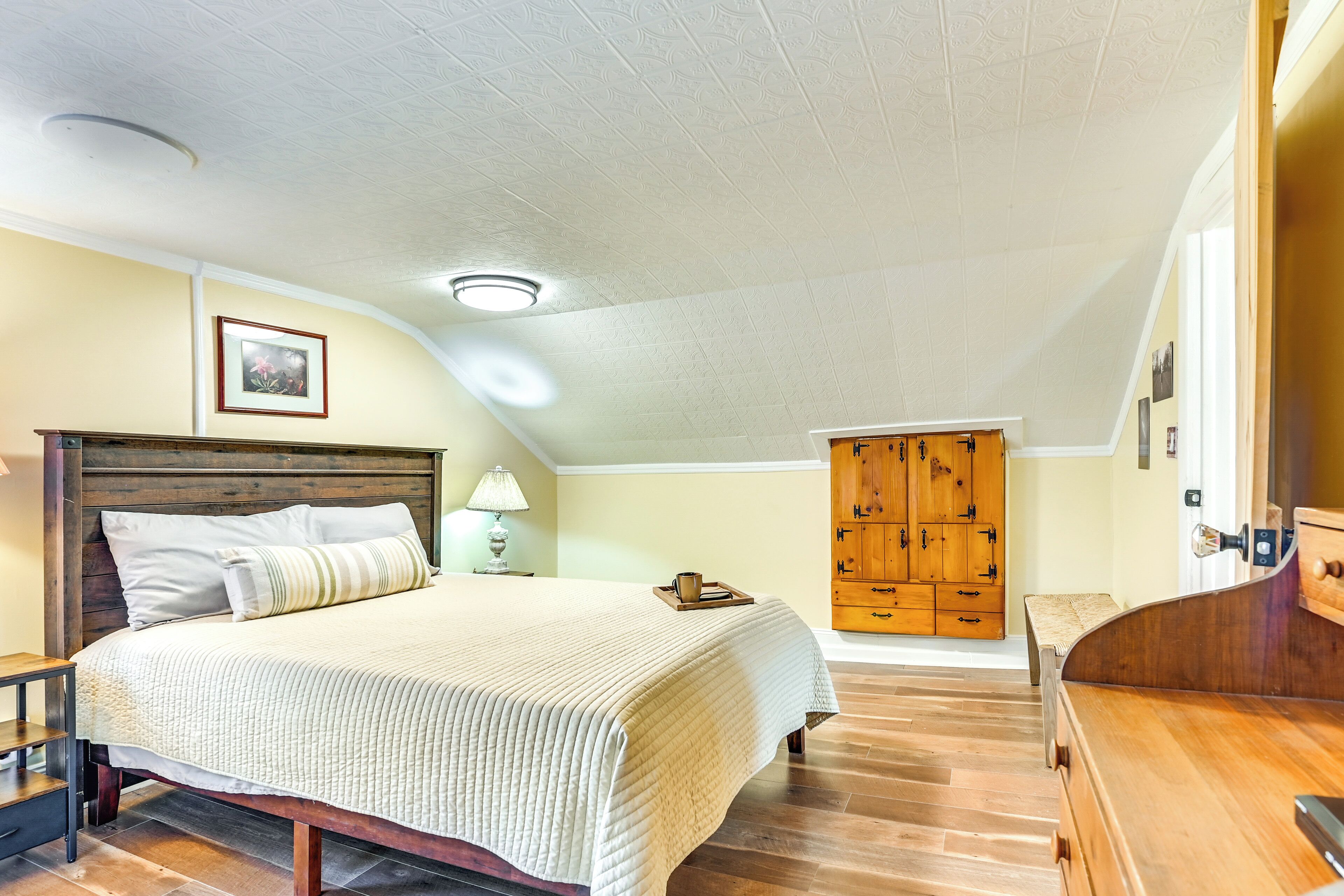 A bedroom with a large bed, wooden wardrobe, and a wooden bench.