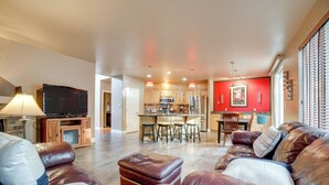 A living room with a leather sofa, ottoman, and a television. - Mtns Await: Reno Escape w/ Yard & Pool Table! (Reno)