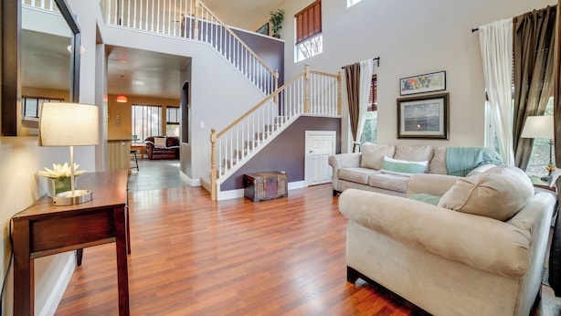 A spacious living room with hardwood flooring, a staircase, a beige sofa, and a coffee table. - Mtns Await: Reno Escape w/ Yard & Pool Table! (Reno)