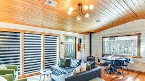 A cozy cabin interior with a wooden ceiling, a leather sofa, a dining table with chairs, and large windows offering a view of the outdoors. - Mtn-view Haven w/ Hot Tub: 9 Mi to Dtwn Bailey (Bailey)