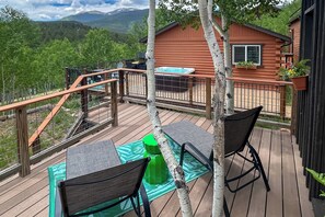 Una terraza de madera con un jacuzzi, dos sillas y una mesa.