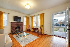 A living room with a fireplace, a television, and a door leading outside. - Walk to The Grandin Theatre: Roanoke Unit w/ Yard! (Roanoke)