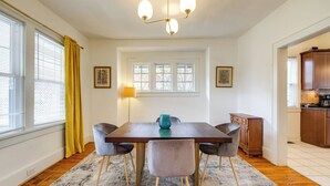 Ein Esszimmer mit Holztisch, vier Stühlen, einem Teppich und einer Kronleuchter.