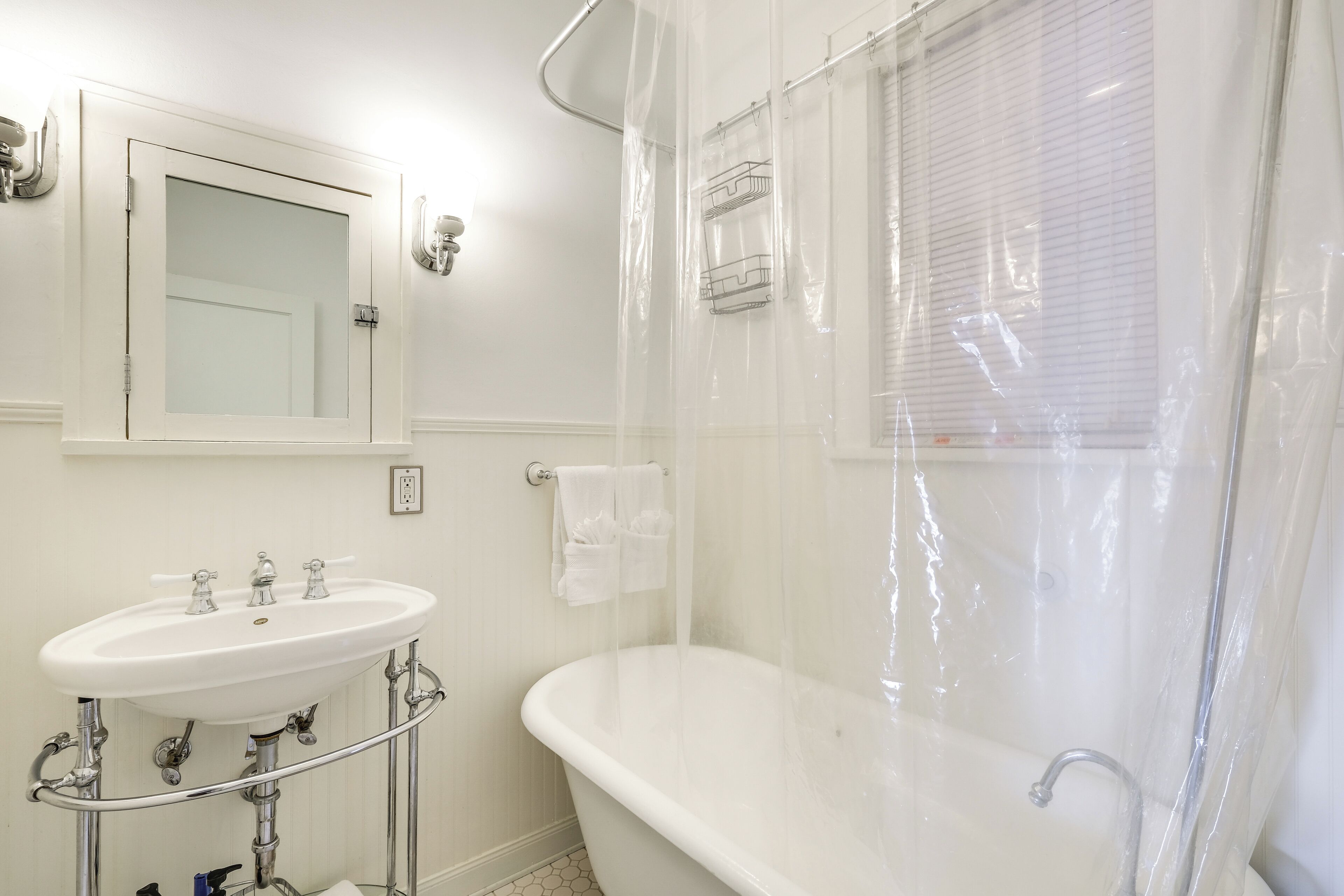 Un baño con lavamanos blanco, bañera y cortina de ducha.