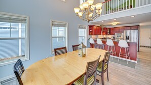 A spacious dining area with a wooden table and chairs, a chandelier, and a kitchen in the background. - St Joseph River, Lake Michigan Access: Luxury Home (Saint Joseph)