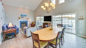A spacious living room with a large wooden dining table, comfortable seating, a fireplace, and a large window offering a view of the outdoors. - St Joseph River, Lake Michigan Access: Luxury Home (Saint Joseph)