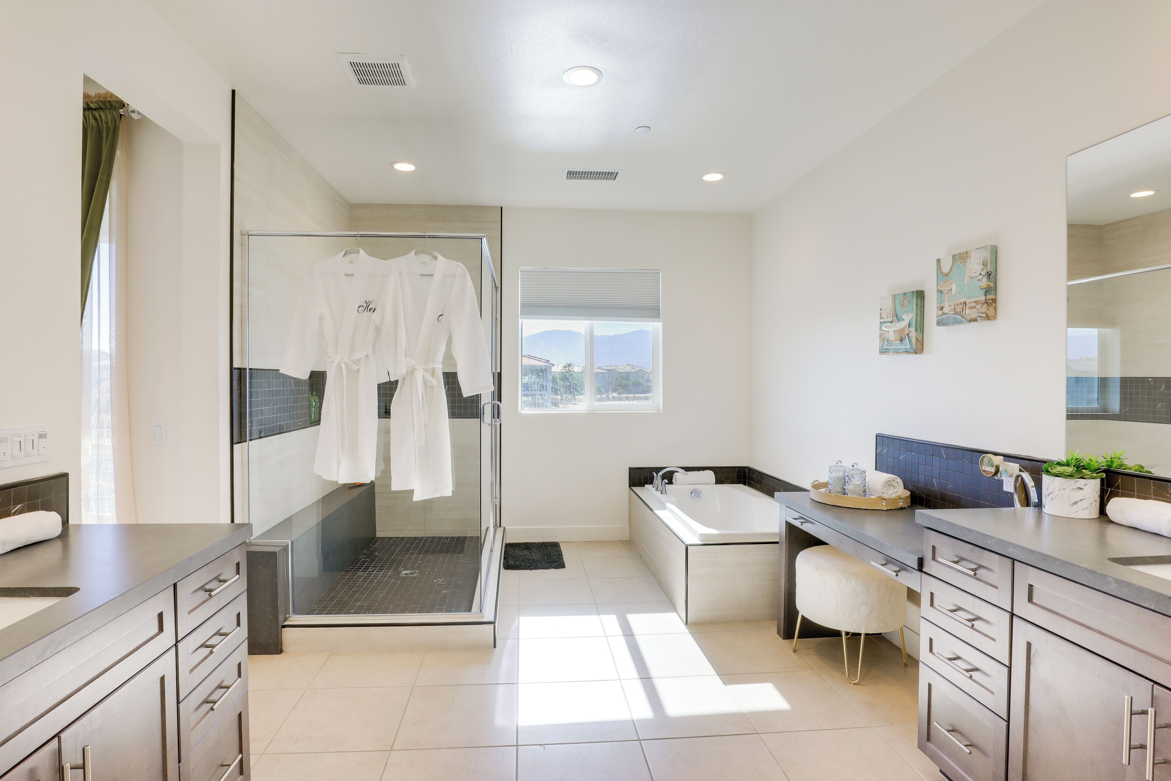 A modern bathroom with a glass shower enclosure, a bathtub, and a vanity with a sink and mirror.