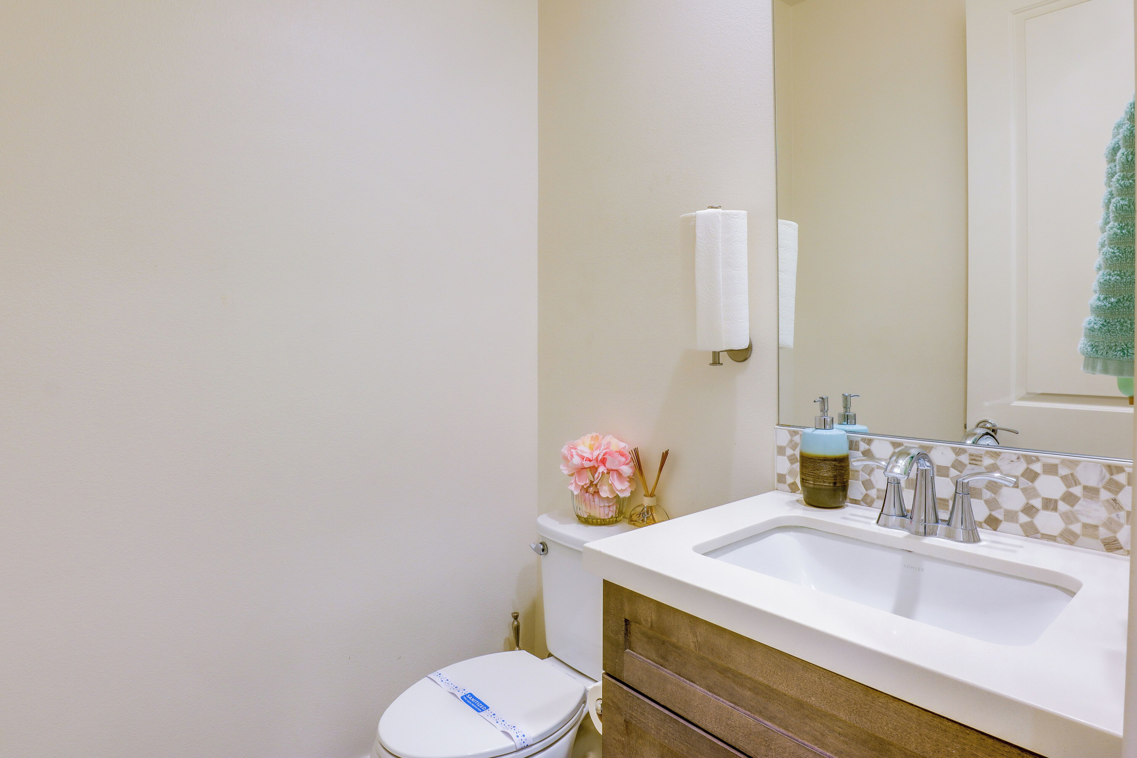 A bathroom with a white toilet, a sink with two faucets, and a mirror above the sink.
