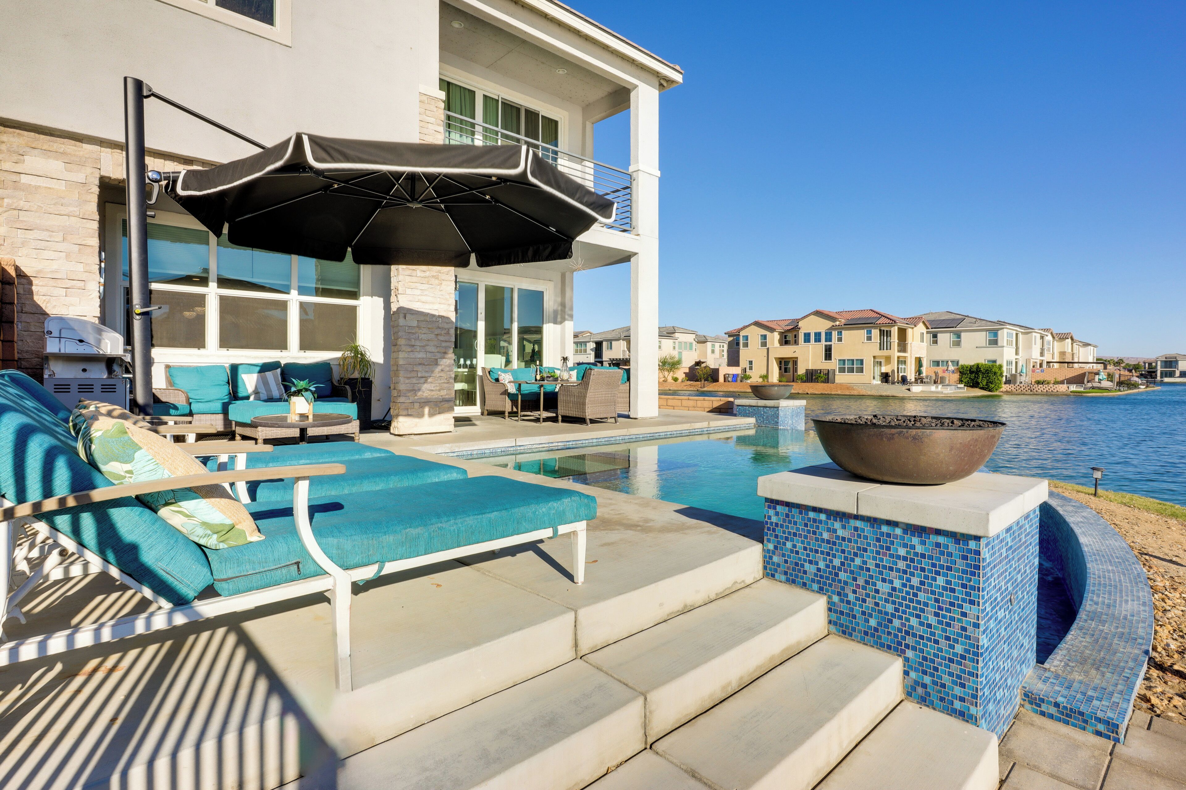 Un espace piscine extérieur moderne, doté de chaises longues et d’un barbecue.