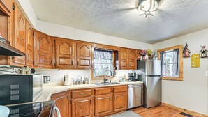 A kitchen with wooden cabinets, a stainless steel refrigerator, and a dishwasher. - On 220 Acres: Home w/ Trails in West Liberty! (West Liberty)