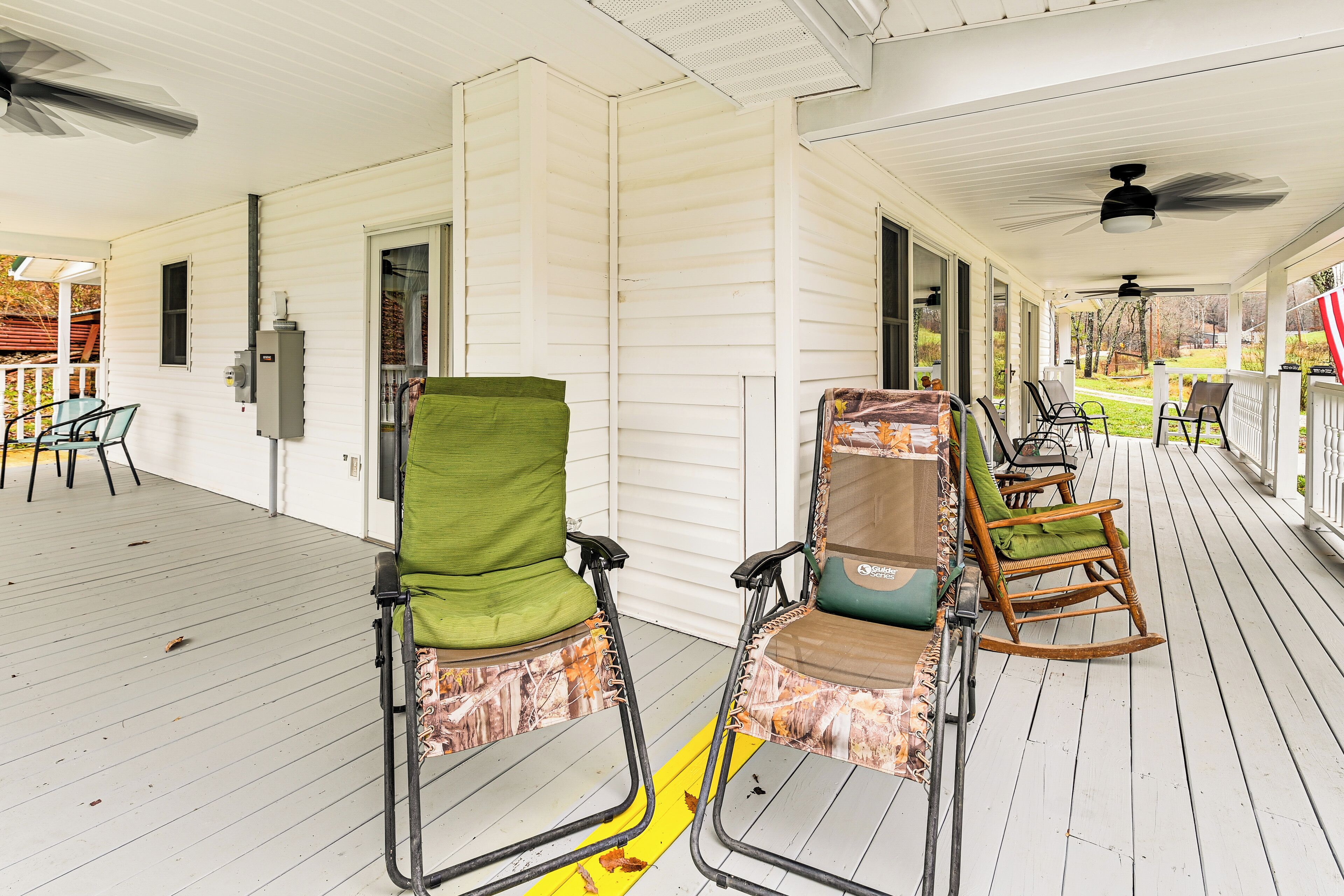 A covered porch with white siding, two wheelchair-accessible chairs, and a rocking chair.