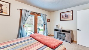 A bedroom with a bed, a fireplace, a door, and a window with curtains. - On 220 Acres: Home w/ Trails in West Liberty! (West Liberty)