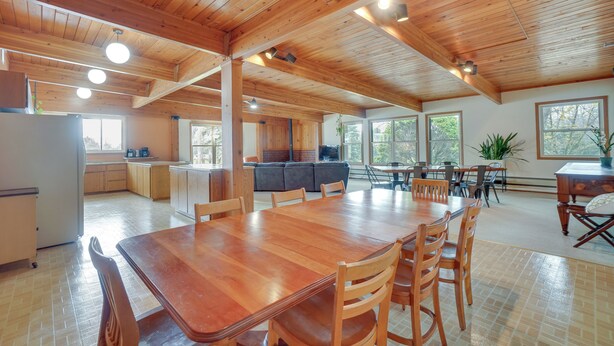 Una cocina amplia con armarios de madera, un comedor con una mesa grande y sillas, y una sala de estar acogedora con un sofá y una televisión.