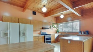 Una cocina con armarios de madera, una isla central, una estufa y un ventanal que proporciona luz natural.