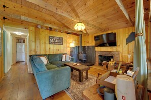 A wooden interior with a sofa, a table, a fireplace, and a television. - 'knotty Kabin' Rustic Waterboro Cabin By Lake (Waterboro)