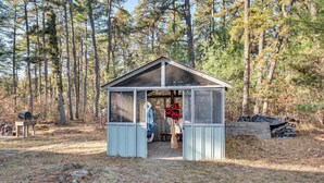 A small wooden cabin with a glass door, surrounded by a forest.