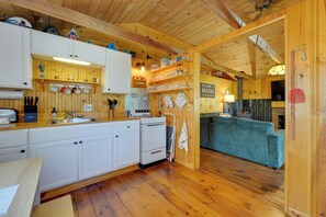 A wooden interior with a kitchen, dining area, and a sofa. - 'knotty Kabin' Rustic Waterboro Cabin By Lake (Waterboro)