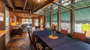 A wooden cabin interior with a dining table set for four, a sofa, and a kitchen area. - Steps to North Hampton Beach: Cottage w/ Deck! (North Hampton)