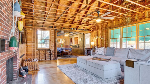 A spacious living area with a wooden ceiling, a fireplace, and a large window. - Steps to North Hampton Beach: Cottage w/ Deck! (North Hampton)