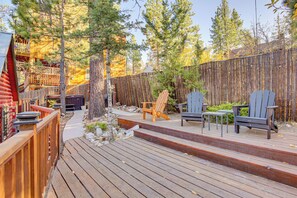A wooden deck with outdoor seating, surrounded by a bamboo fence and trees.