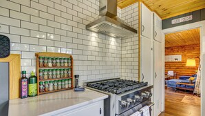 A kitchen with white tiled backsplash, stainless steel appliances, and a spice rack.