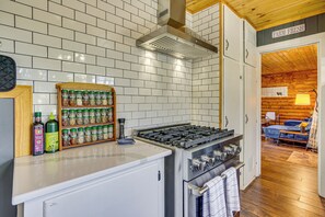 Cozinha com painel de azulejos brancos, eletrodomésticos de aço inoxidável e um espaço para temperos.
