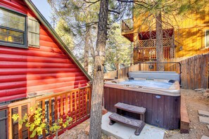 A hot tub in a backyard with a wooden deck and a red building.