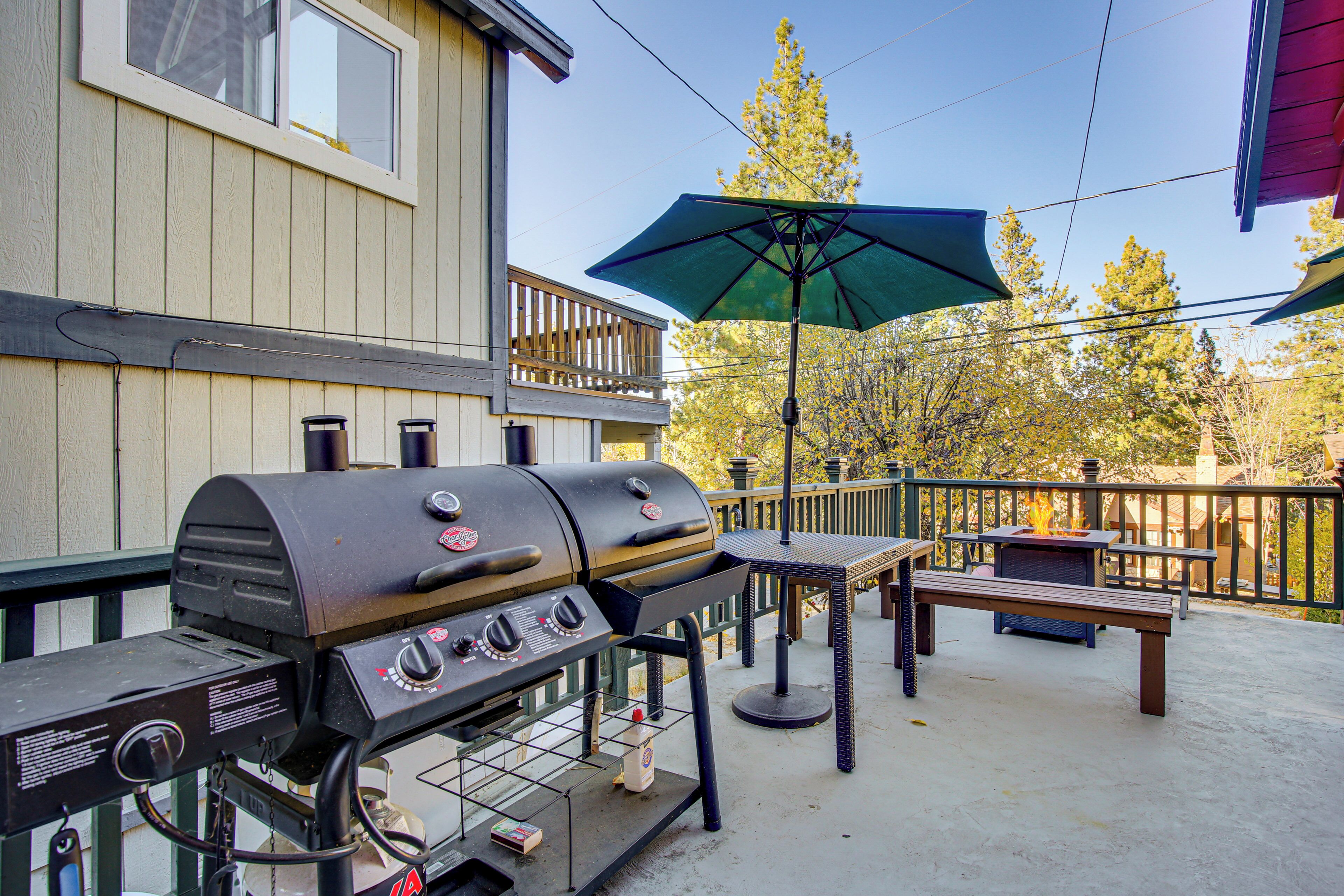 A barbecue grill, outdoor table, and umbrella on a patio.
