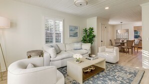 A spacious living room with a white sofa, a coffee table, and a dining area in the background. - Walk Downtown & Canton Street: Roswell Retreat! (Roswell)