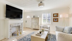 A living room with a fireplace, a flat-screen TV, a sofa, a coffee table, and a lamp. - Walk Downtown & Canton Street: Roswell Retreat! (Roswell)