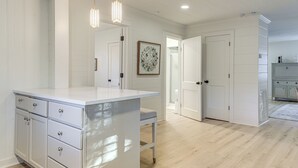 A spacious kitchen with white cabinetry, a central island, pendant lighting, and a view into adjacent rooms. - Walk Downtown & Canton Street: Roswell Retreat! (Roswell)