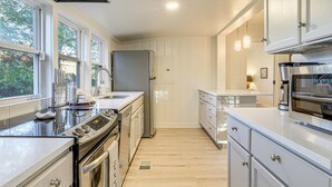 A modern kitchen with stainless steel appliances, white cabinetry, and large windows. - Walk Downtown & Canton Street: Roswell Retreat! (Roswell)