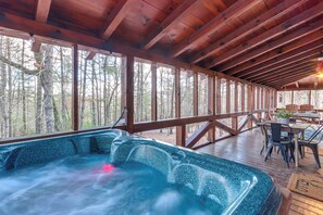 Un espace avec un bain à remous, une terrasse en bois et une vue sur la forêt.