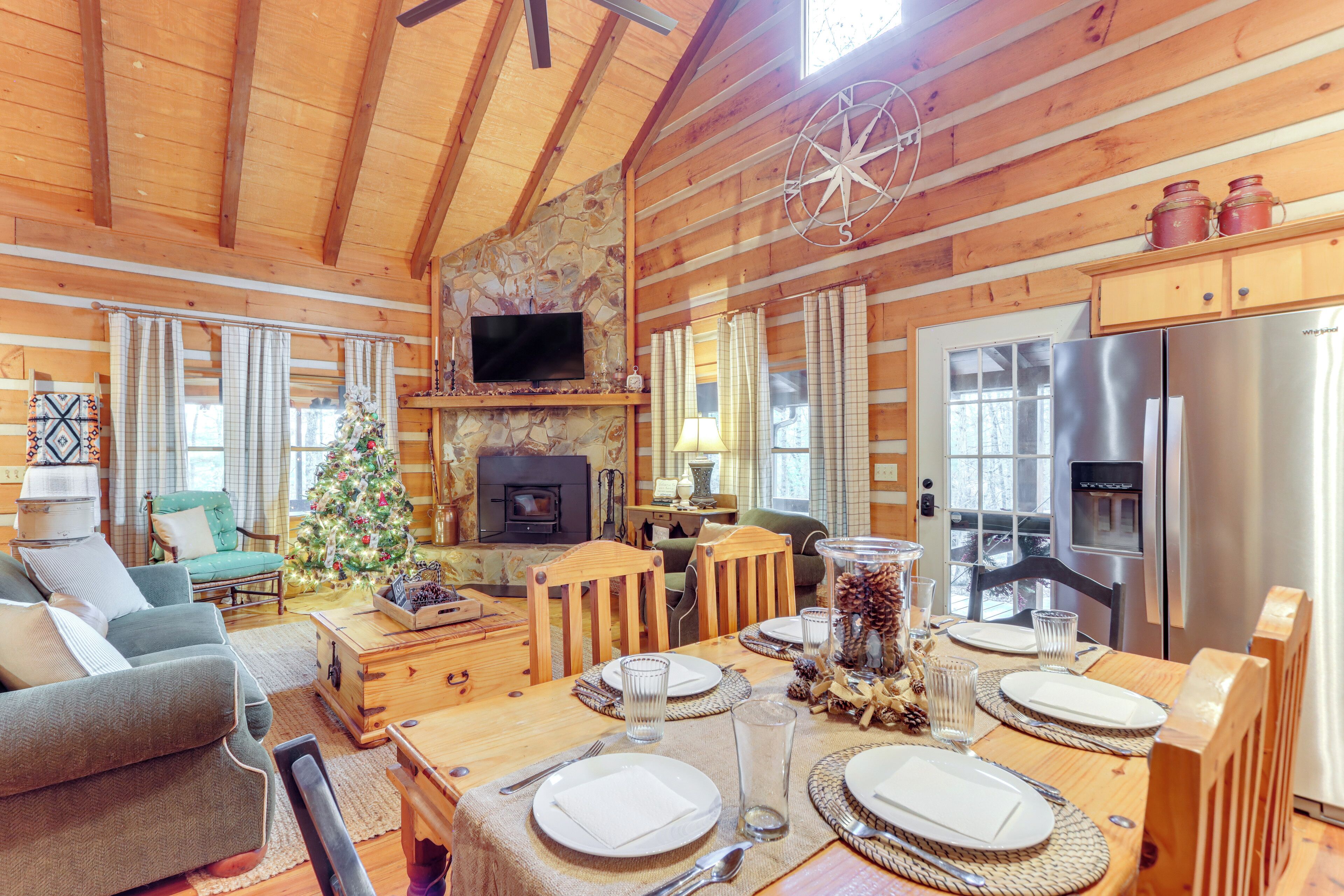 A cozy cabin interior with a dining area, fireplace, and modern kitchen.
