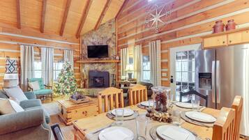 A cozy cabin interior with a dining area, fireplace, and modern kitchen.