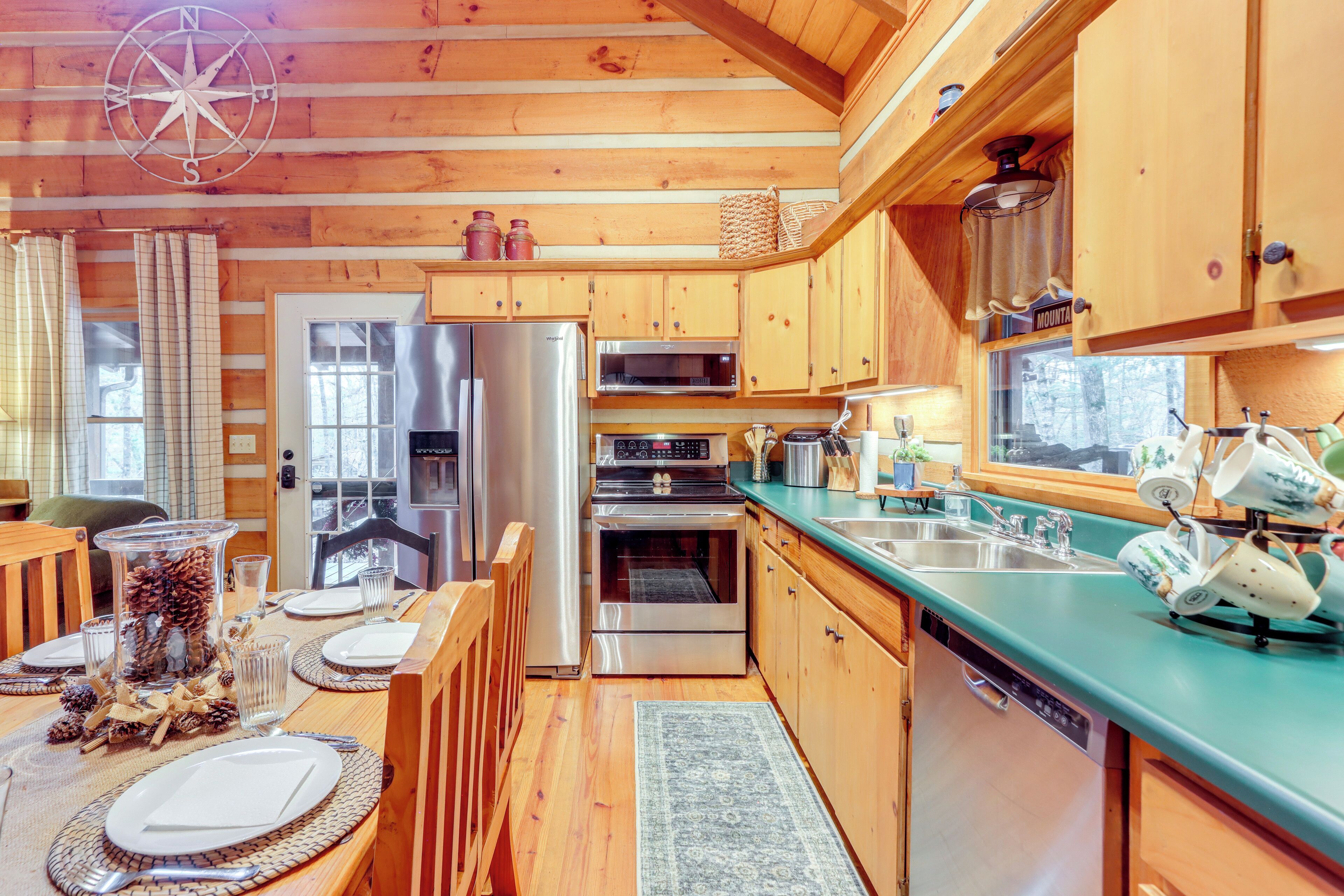 Une cuisine rustique, située dans une cabane en bois, avec un coin repas, des appareils en acier inoxydable et un plan de travail vert.