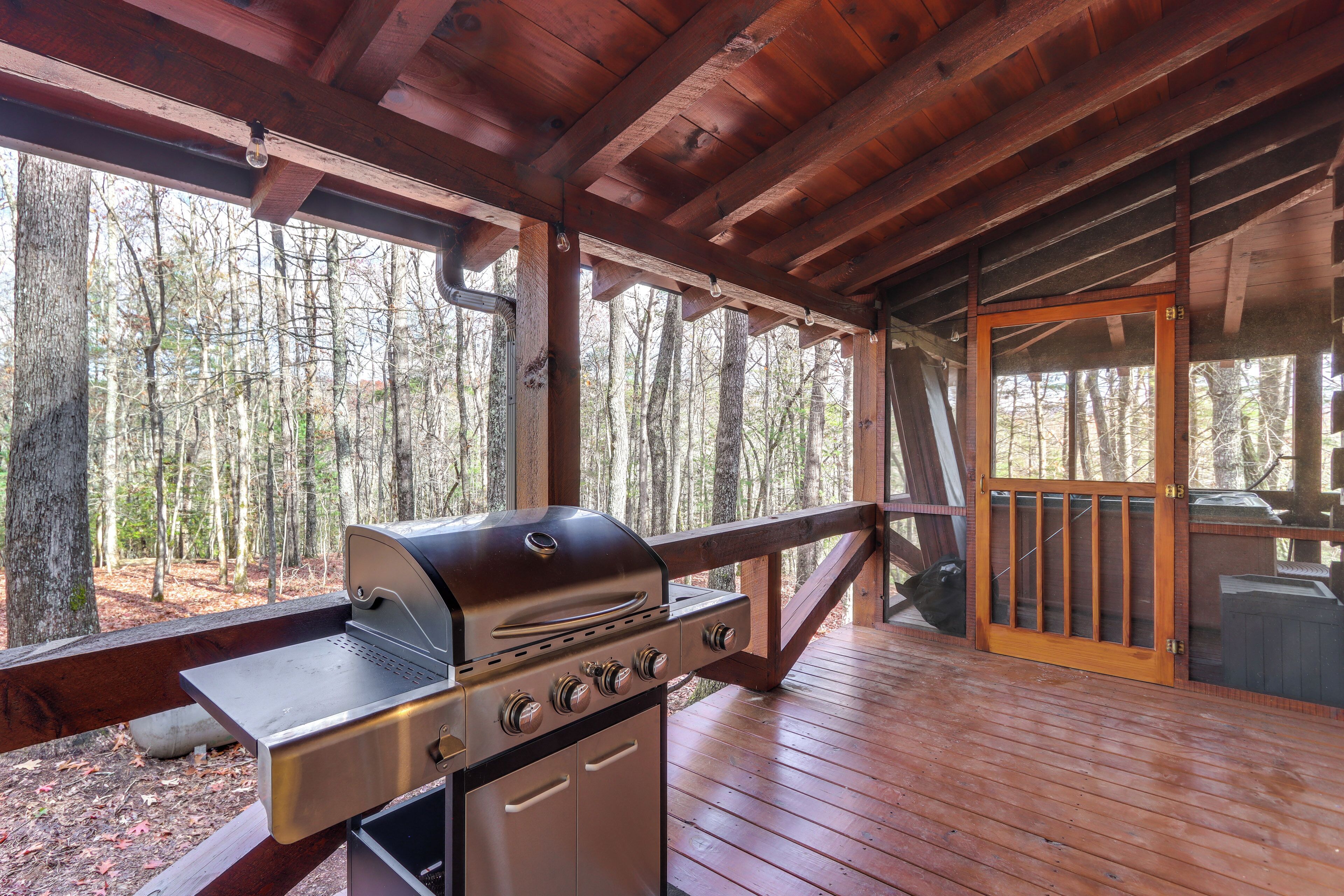 An outdoor wooden deck with a built-in grill and a wooden door leading to a covered area.